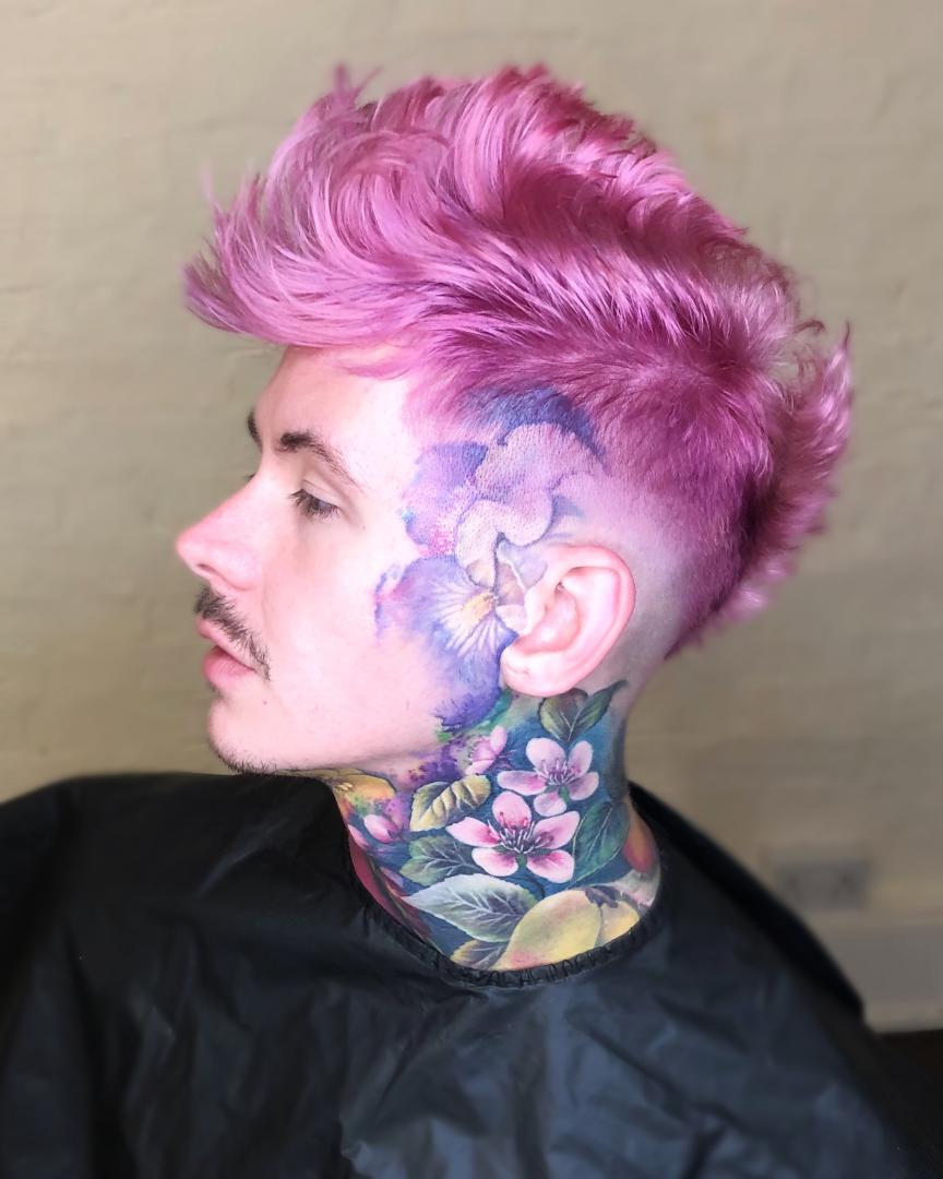 Person with pink hair and tattoos on neck and face.