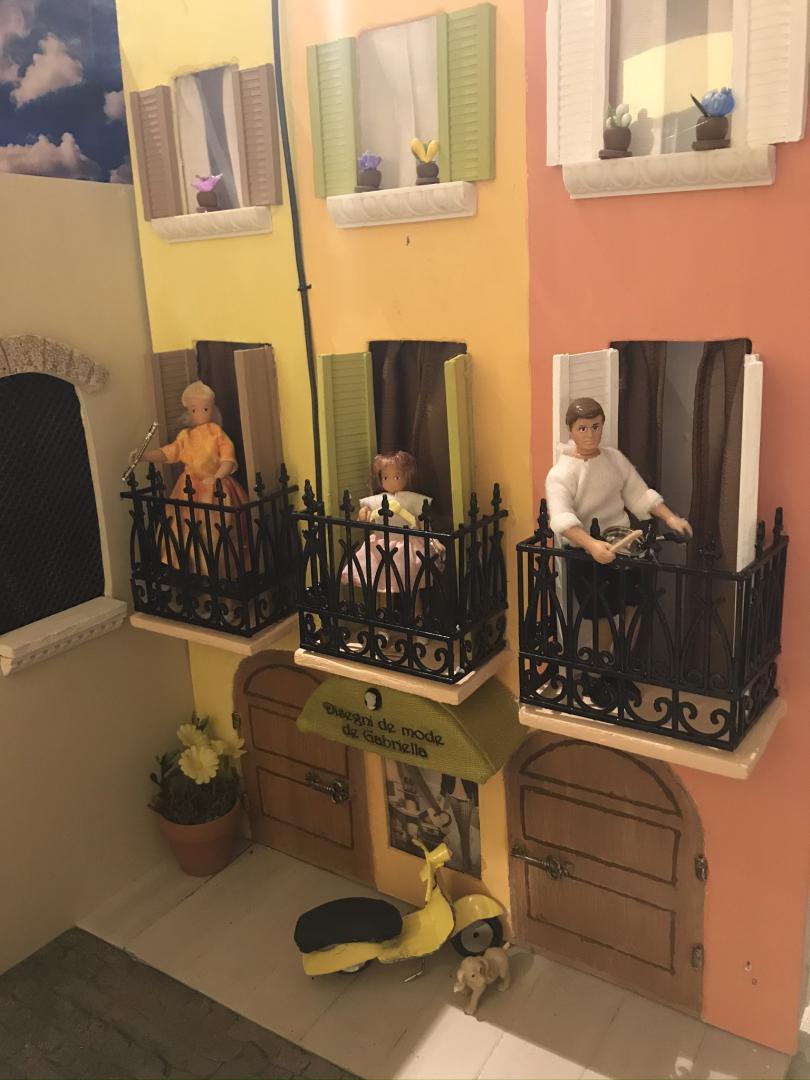 Diorama with three figurines standing on balconies.