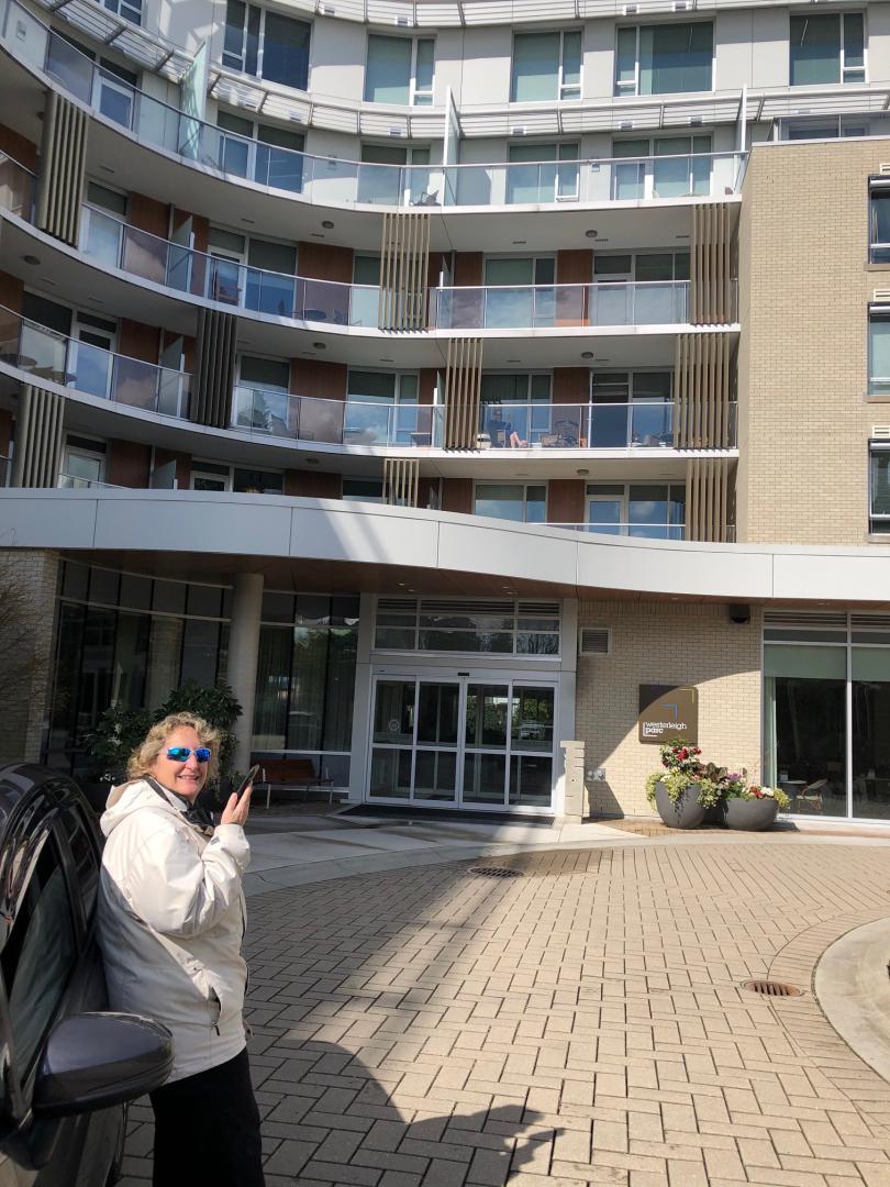 Woman standing outside building speaking into mobile phone.