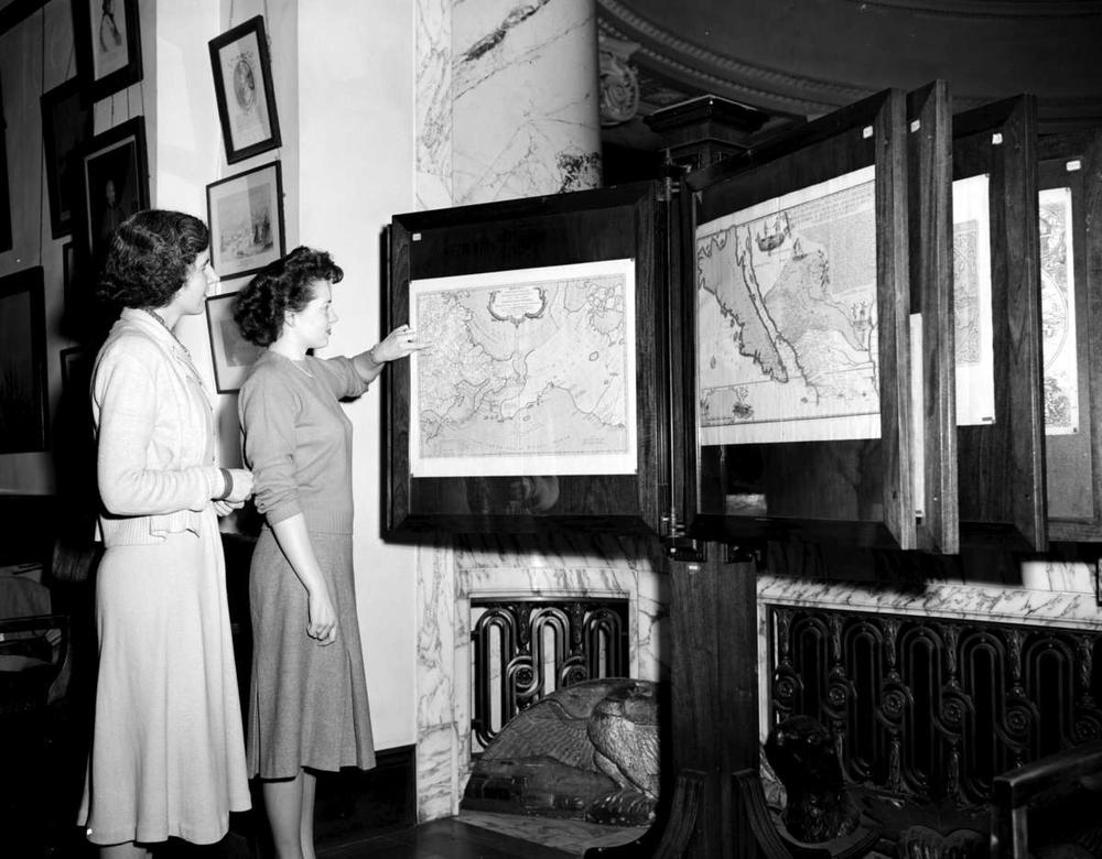 Circa 1949, two staff members look at maps in the exhibit room of the provincial archives back when they were still located in the legislative buildings. 