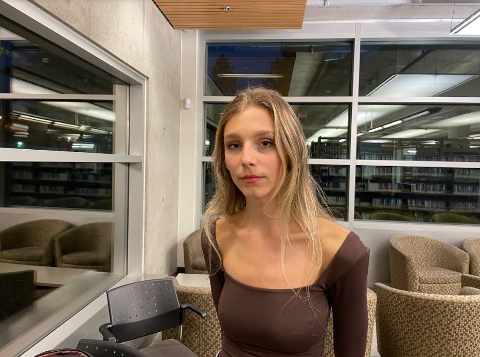 Young adult, standing in a library.