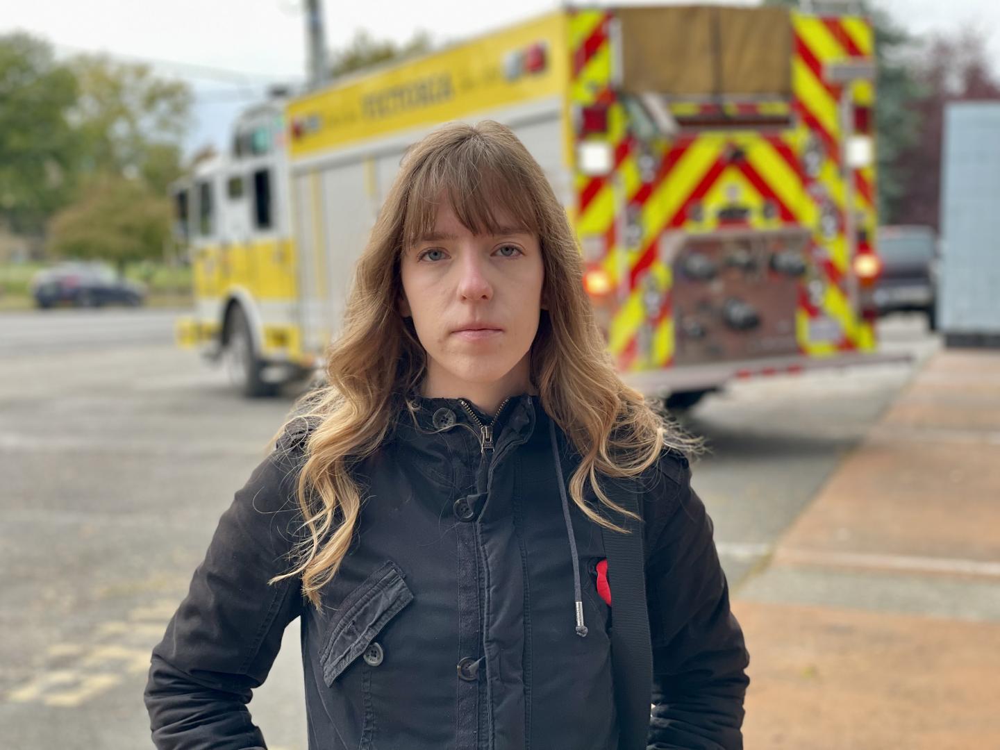 Young adult, standing in front of a fire truck.