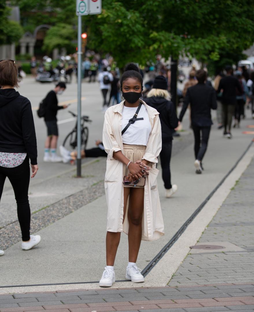 Woman standing on the street, wearing a mask.