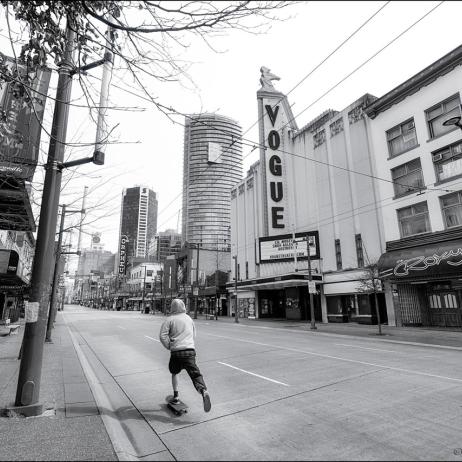 Person skate boarding down empty city street.