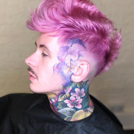 Person with pink hair and tattoos on neck and face.