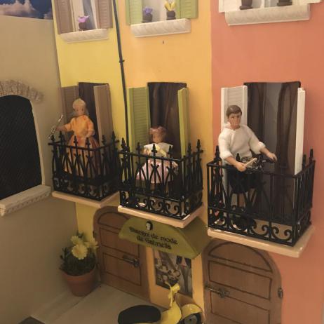 Diorama with three figurines standing on balconies.