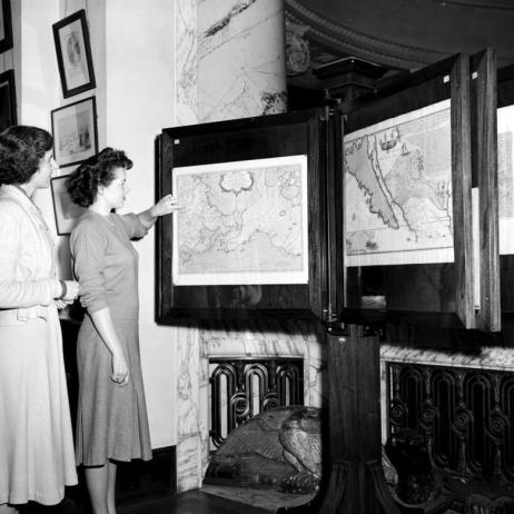 Circa 1949, two staff members look at maps in the exhibit room of the provincial archives back when they were still located in the legislative buildings. 