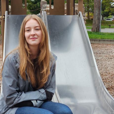 Young woman, sitting on a slide in the park.