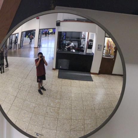 Young man, taking a photo of himself in a mirror at the museum.